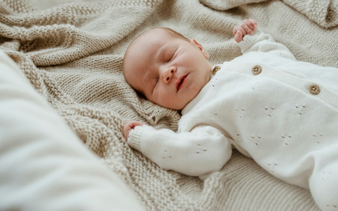 Schlafendes Neugeborenes auf einer hellen Strickdecke