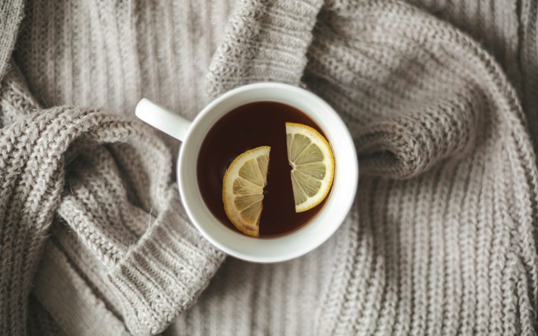 Tasse Tee mit Zitronenscheiben auf einer Strickdecke