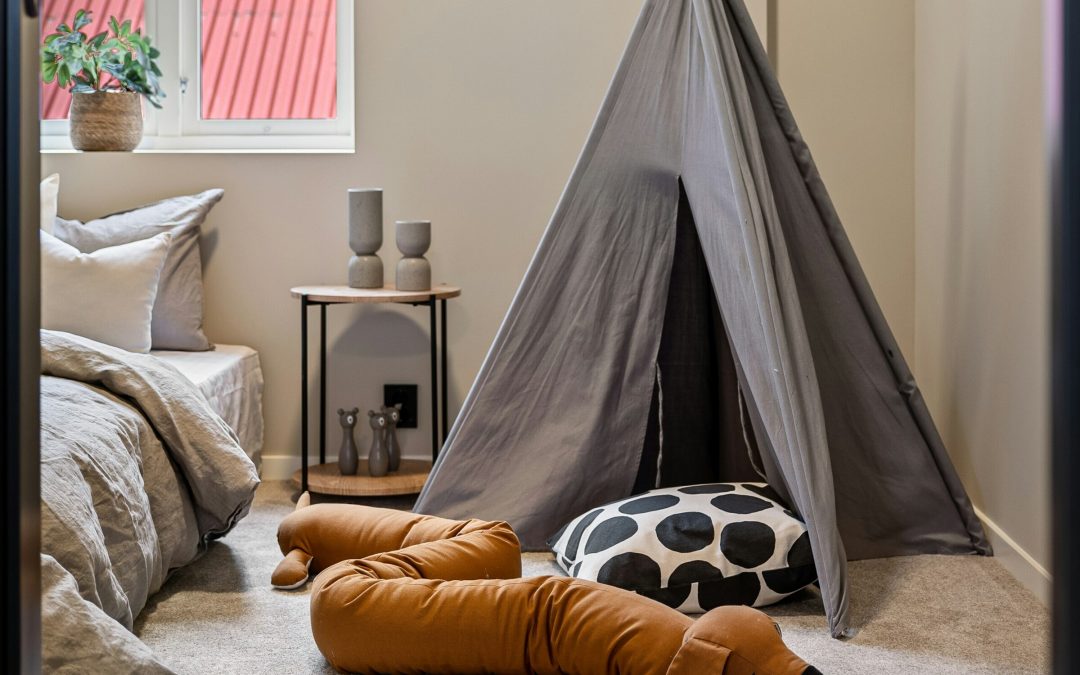 Graues Tipi-Spielzelt im Kinderzimmer mit Kissen und Kuscheltier