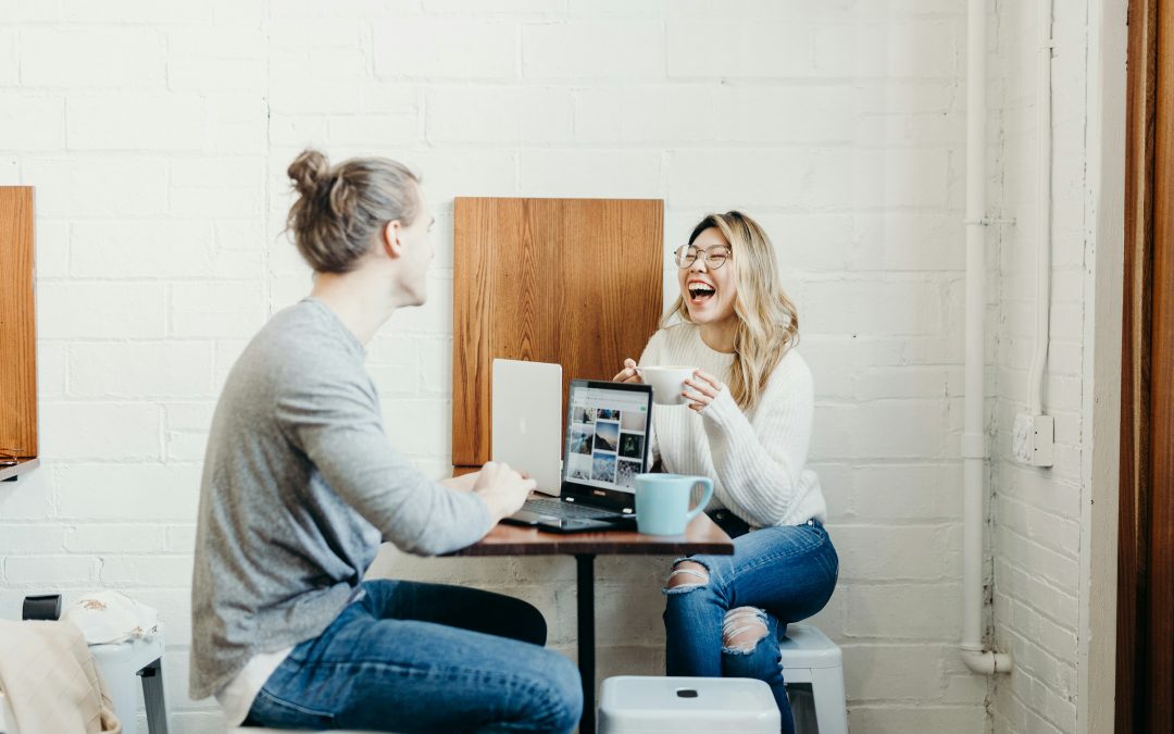 Zwei Kollegen lachen am Laptop im Büro