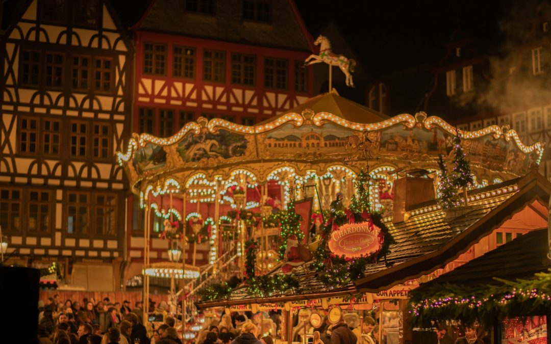 Ein hell beleuchtetes Karussell auf einem abendlichen Weihnachtsmarkt vor Fachwerkhaeusern
