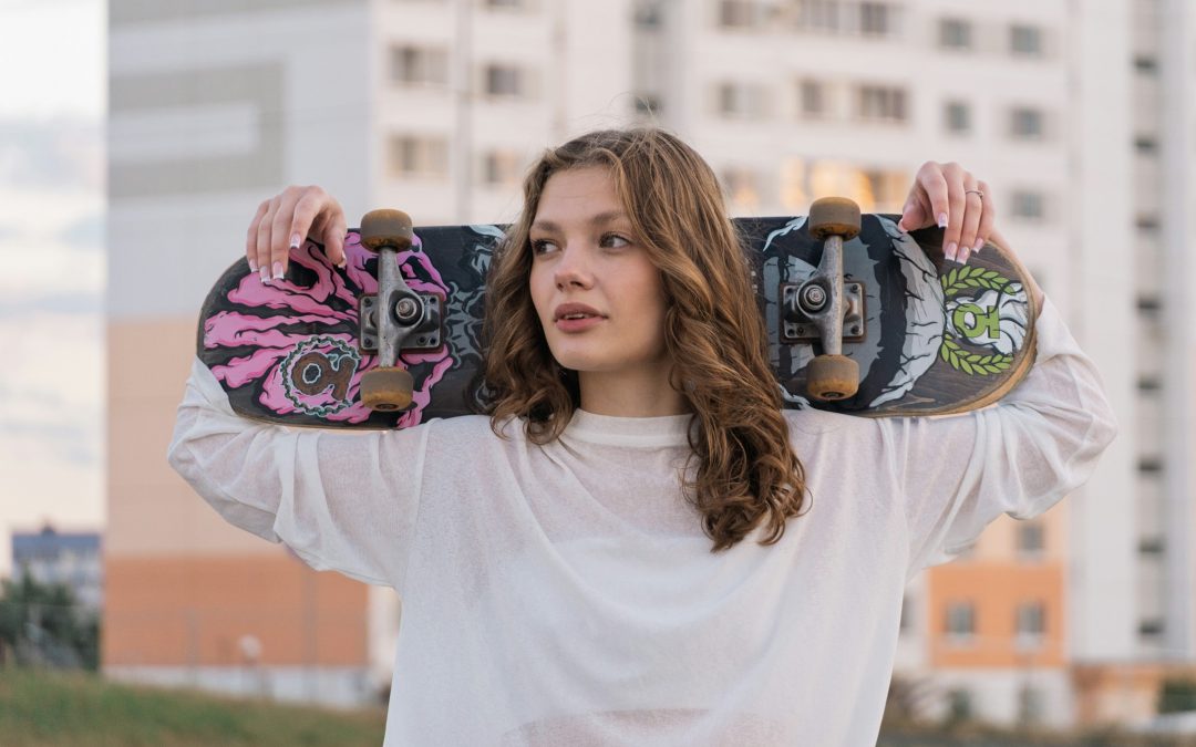 Jugendliche mit Skateboard auf den Schultern, im Hintergrund Wohnhaeuser