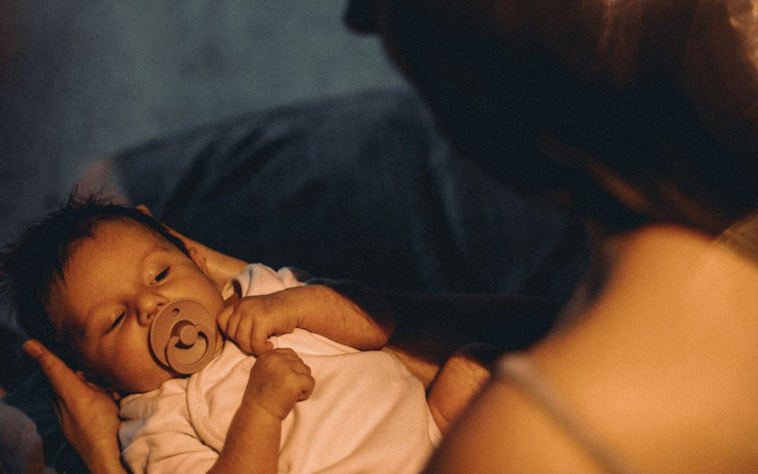 Ein unruhiges Baby liegt im Arm einer erwachsenen Person