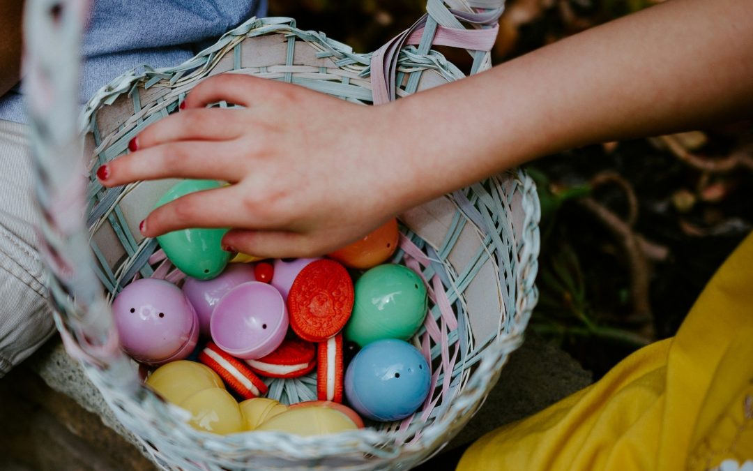 Kinderhand greift in einen Korb mit bunten Ostereiern